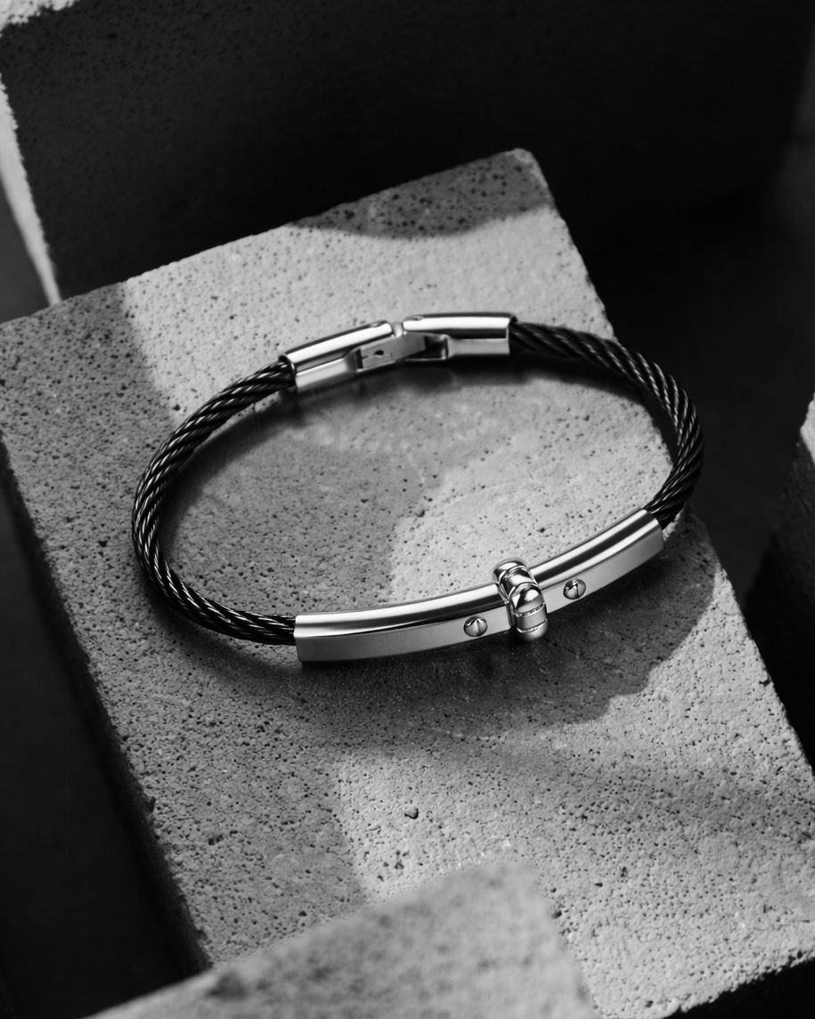 Black leather bracelet with silver clasp on a textured surface