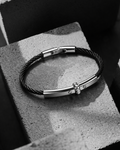 Black leather bracelet with silver clasp on a textured surface
