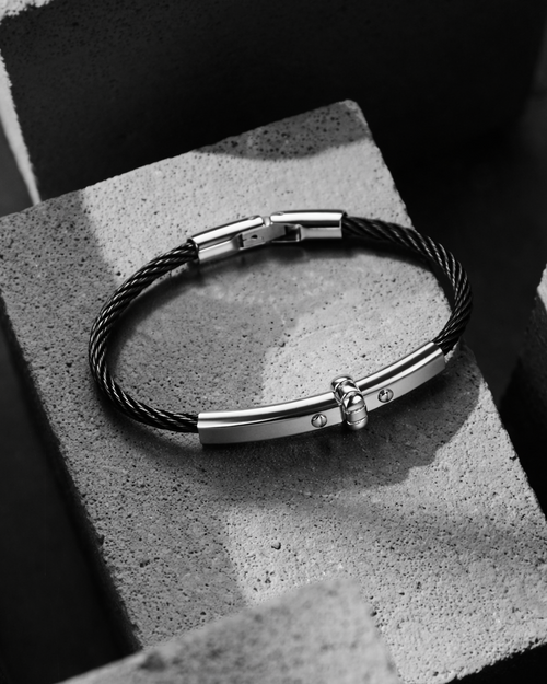 Black leather bracelet with silver clasp on a textured surface